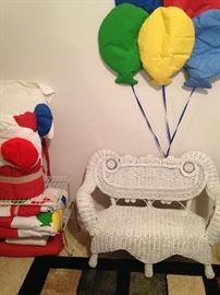 A child's white wicker settee; balloon wall art and bedding