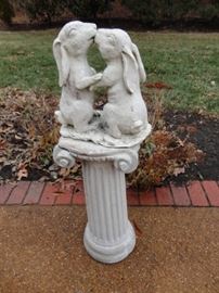 Concrete pedestal and kissing bunny rabbits.
