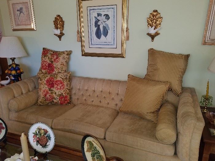 Vintage beige sofa, decorative plates, throw pillows, art, and more. 