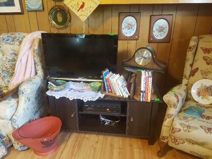 Panasonic flat screen television, television stand, books, mantle clock, and more.