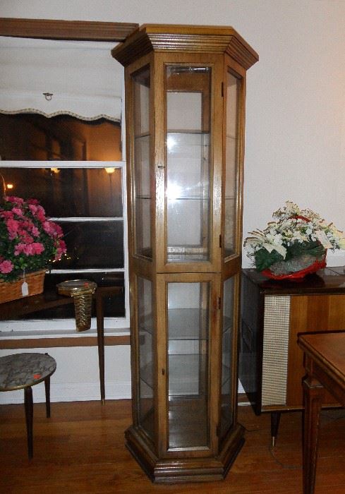Six sided curio cabinet with glass shelves, lighted.