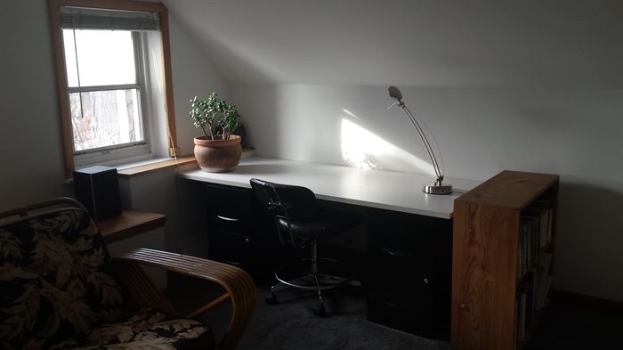 Student's corner: desk top resting on 2 filing cabinets with unfinished wooden bookcase and desk chair.
