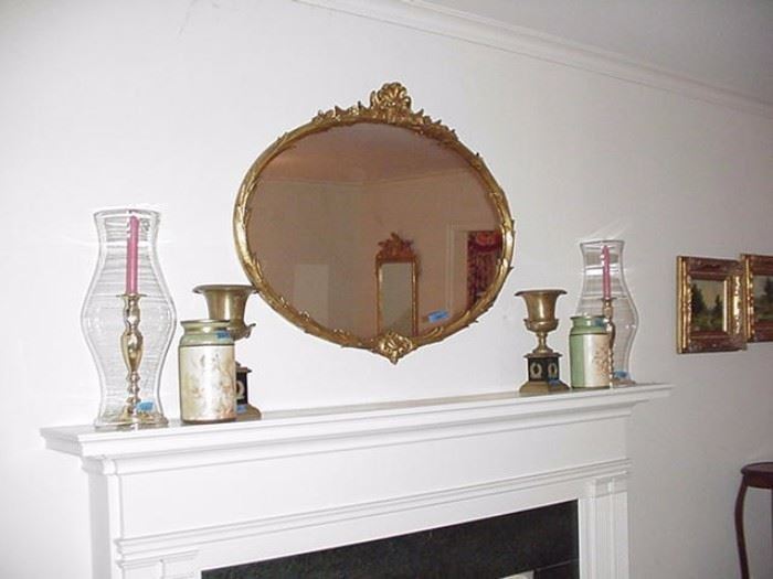 Oval gold-leaf mirror,  brass candlesticks