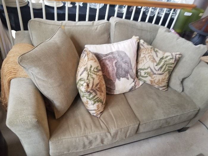 Grey loveseat, shown with some of the many decorative pillows