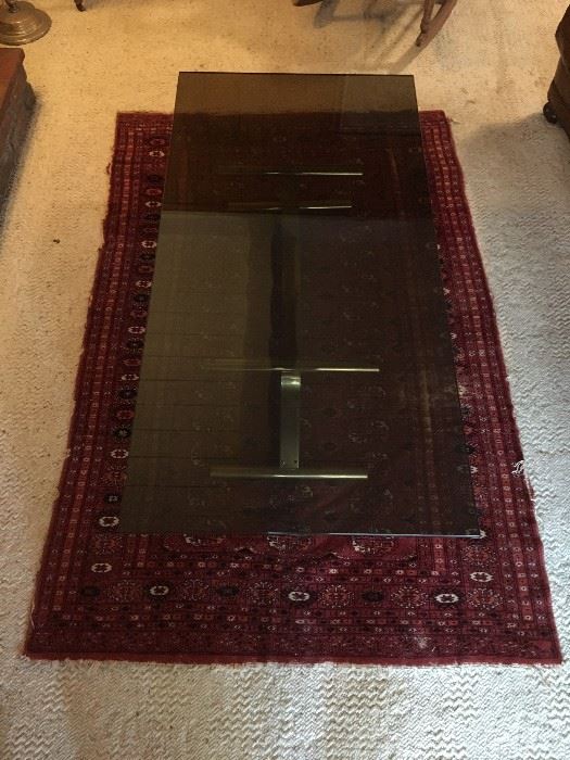 Antique rug and Mid Century Modern glass and brass- colored coffee table.