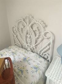 Twin white wicker headboard with a glimpse of the side table. 