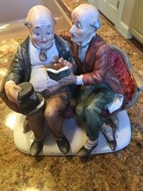 Collectible men sharing a book on a bench figurine