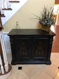 Black hall cabinet with hand painted embellishments. 
