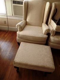 One of a pair of white wing chairs with ottomans