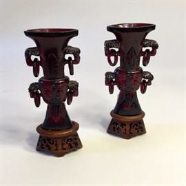 Pair of carved cherry red amber cabinet vases on stands.