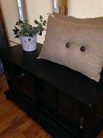 Black TV stand; pair of tan pillows