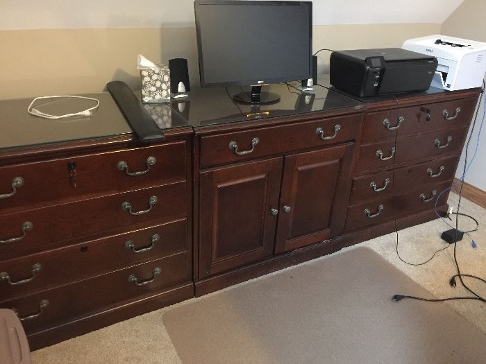 Two lateral file cabinets with locking drawers.  Middle unit has pull-out drawer for a keyboard and storage underneath.  All three have glass tops.  Being sold separately.  Nice cherry finish.