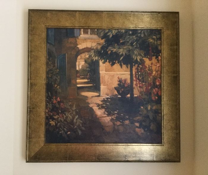 “Courtyard in Provence” artwork of courtyard scene with arched doorway, trees, & multiple blooming plants, set in gilt frame