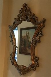 Contour shaped aged gold mirror with silver acanthus leaves curled over the sides, double spiral at top and bottom
