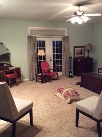Antique wood vanity with attached mirror. Wooden rocking chair with dragonfly upholstery. Wood cabinet. Brown & Bigelow “Cathedral of St Amiens” vintage framed lithograph. Cedar lined Lane hope chest for storage.