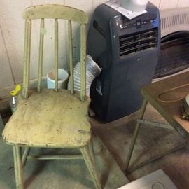 LG air conditioner, Comfort Glow wall heater, spindleback chair with original finish. Metal folding table for hunting and camping has faux wood grain finish top.
