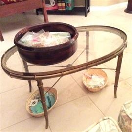 Regency style brass coffee table has inset glass top and features a bamboo pattern. Assortment of brooches, necklaces, earrings and jewelry.