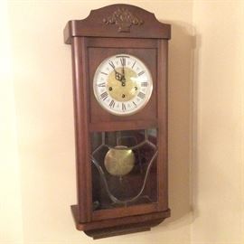 West German pendulum wall clock has an elegant wood case. Curved leaded beveled glass adorns front door. Convex glass covers ornate clock face. Chimes at quarter, half and full hour.  Resonant chime options include Westminster, Ave Maria and silent. Quality heirloom timepiece has original key.