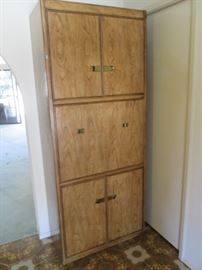 Drop-Front Bar Cabinet in Campaign Style, burled-wood look. Lighted with plenty of room for upper and lower storage and display. Size: 33" X 17" X 80"