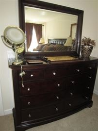 Large dresser with mirror has matching nightstands and Queen bed