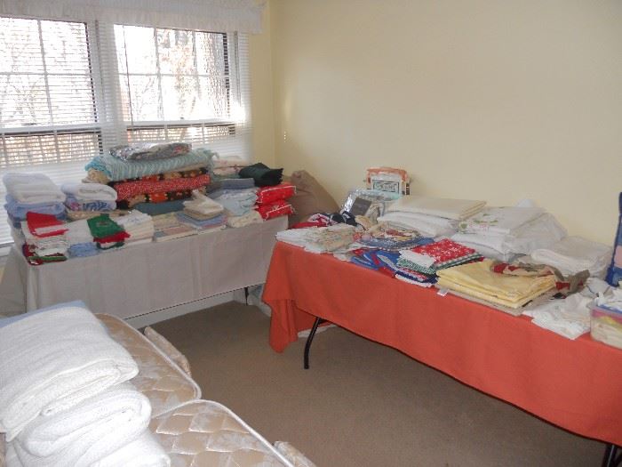 Large selection of linens including sheets, tablecloths, towels, throws and blankets