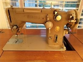 A vintage Singer 319W sewing machine, which folds neatly into its wooden cabinet after use.