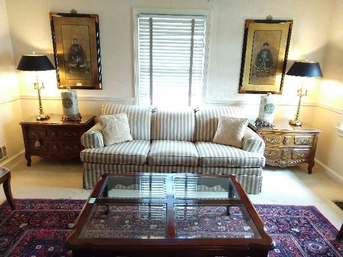 One of a pair of Ethan Allen upholstered sofas, flanked by a pair of vintage Henredon Villandry French Louis-XV-Style walnut chests; they measure 34" wide x 19 1/2" deep x 24 1/2" tall. There is an  Ethan Allen mahogany coffee table, with beveled glass inserts and a 3-drawer mahogany sofa table. Above the Henredon chests, are a pair of Chinese ancestral paintings, on cork, also a pair of 3-way vintage Stiffel lamps and pair of Asian porcelain vases, on brass bases.