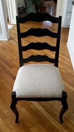 Kitchen table chairs are black with white upholstery.