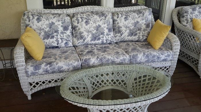 Wicker patio sofa and coffee table with glass top.