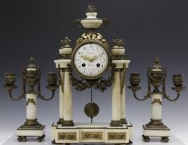 Antique French Bronze Mounted Marble Clock Candle Set. Fine quality 19th century garniture set featuring creamy white marble with gold gilt dore bronze mounts with floral swags and fruit topped urns. Clock features four columns with urn top decoration. Enameled face reads Planchon Paris. Matching candlesticks with dual arms and centers with fitted stoppers. All pieces resting on turned bun style feet. Clock measures 15″ x 9″ Candelabras measures 9 1/2″ x 6 1/2″ | Good condition with light wear.