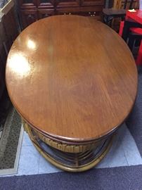  Very unusual coffee table, it's oval oak top with a rattan base.   It measures 79 inches long by 39 inches wide, 21 inches tall. 