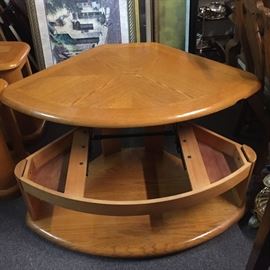 This unusual coffee table is round it on the front will fit in the corner.  The top lifts up on the hinge and spring for storage. There is a chip near the corner 