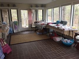 Sunroom full of linens lots are  vintage and  Fabric .             Please note rugs not for sale 