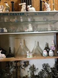 Mid-century display case filled with candle holders and antique funnels.