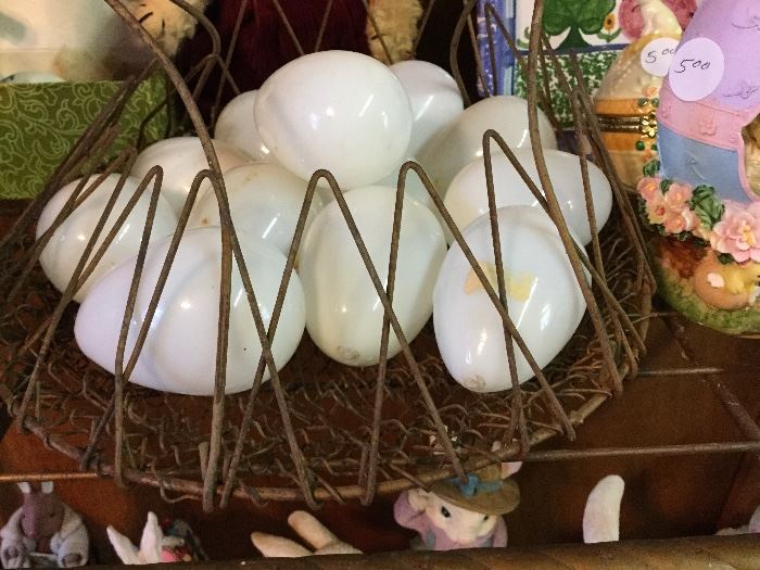 A dozen hand blown nesting eggs in a wire basket.