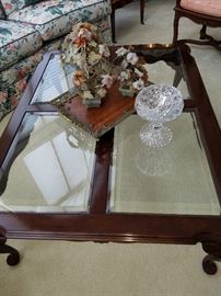 Beveled glass inset coffee table in mahogany finish displays stone floral arrangements and a brilliant cut glass vase