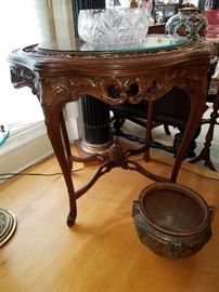 Carved table with inlaid top protected by oval glass. Jardiniere signed Roseville. 