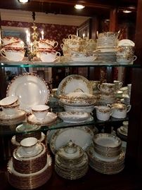 Sets of dishes.  The white and gold is Noritake. The set with red is Royal Doulton