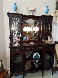 Ca. 1895 carved ornate sideboard or display cabinet. Mirror backs in the top. Mahogany finish.