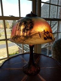 Reverse painted table lamp (old one, but no signature found).  Has obverse beaded surface over trees.  Scene is rural with sheep coming through fence as sun sets