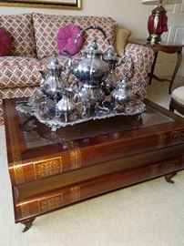 Book form coffee table with ornate silverplate tea service on top, complete with kettle on stand