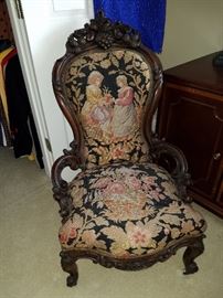 19th Century ornately carved chair with hip rests.  Upholstered in antique needlepoint.