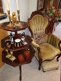 Three tier table with pierced edges, beside a Victorian style arm chair with tufted upholstery.