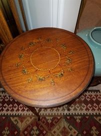 Paint decorated table in front of the Howard Miller tall case clock