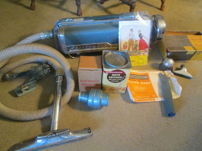 Vintage Electrolux vacuum cleaner with attachments shown plus a large garment bag to use with moth crystals