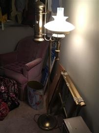 This is a standing brass lamp with a cute retro upholstered chair in he background. The chair has a match in another room to form a two-piece set.