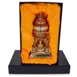  Bouquet Of Lilies Faberge Inspired Egg with Presentation Box (1899) | Measures 6" H x 2.5" Diameter | Enamel, Gold Plated Pewter Hand Painted, includes a custom Gift Box | This hand-painted sparkling egg is adorned with a high-polished enamel with golden trim. The egg opens on a hinge and closes shut with a magnet, to keep the box securely shut. The piece comes in a beautiful gift box. History: The Bouquet of Lilies Clock Egg (or the Madonna Lily Egg) is a jeweled Easter egg made under the supervision of Peter Carl Faberge in 1899 for Tsar Nicholas II as an Easter gift to his wife, the Alexandra Fyodorovna. It is currently held in the Kremlin Armory Museum in Moscow and it is one of the few Royal Russian eggs that have never left Russia. The egg-shaped decorative clock and its rectangular pedestal are decorated with translucent enamel on a guilloche background. The body of the clock is divided into twelve parts which are outlined in diamond-studded stripes. The belt of the dial which 