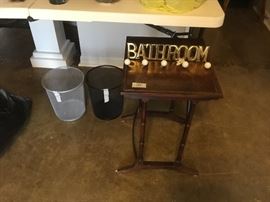 Small table, wire wastebaskets, and bathroom wall decor 