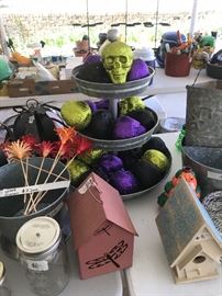 Tiered metal serving tray filled with skeleton heads in various colors; several different sizes of metal decor pieces; bird houses