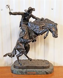 High quality late 20th century solid cast bronze sculpture of a cowboy with upraised arm riding a bucking horse, from the original entitled "Bronco Buster" by Frederic Remington, on a green marble base, 22" x 17" x 6 1/2"